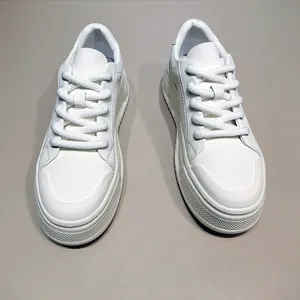 Κοντινό πλάνο λευκών sneakers με χοντρή σόλα και φαρδιά κορδόνια.