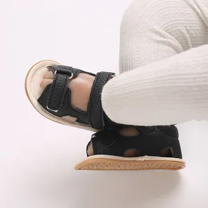 Gedetailleerd overzicht van zwarte baby sandalen met zachte zolen en witte legging