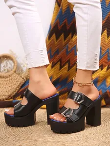 Detailed side view of black platform sandals with chunky high heels and silver buckles
