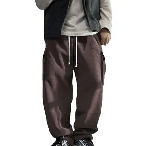 Detail view of men's brown corduroy cargo pants with loose fit and side pockets design