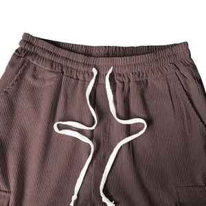 Primo piano di pantaloni di velluto a coste marroni da uomo con elastico e coulisse bianca.
