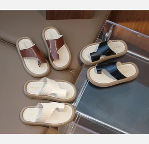 Variedad de sandalias de playa para niños en colores marrón, negro y blanco crema.