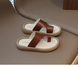 Vista superior de elegantes chanclas marrones para niños sobre superficie de cuero