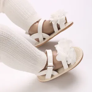 Primer plano de sandalias blancas para bebé niña con flores de tela elegantes