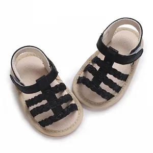 Bovenaanzicht van baby zomersandalen met zwarte gevlochten bandjes en rubberen zolen.
