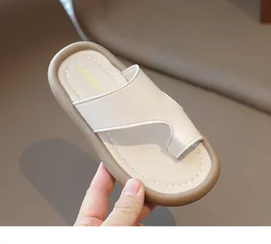 Sandalias de dedo para niños beige sostenidas a mano, primer plano de textura de cuero