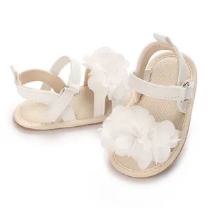 Vista de primer plano de sandalias blancas para bebés con flores de tela detalladas.