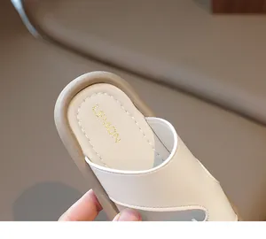 Primer plano detallado de pantufla infantil de cuero crema con logotipo dorado 'LEMON' en la suela.