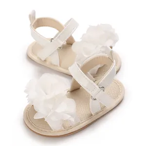 Primer plano detallado de sandalias blancas de princesa para bebé con flores de tela.