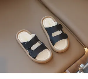 Draufsicht auf neue schwarze Kinder-Sandalen mit Doppelriemen und weicher brauner Sohle.