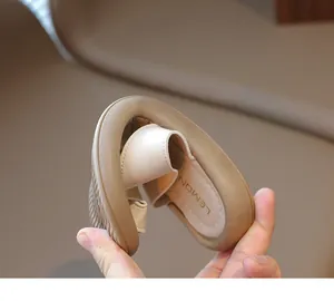 Vista detallada que muestra la extrema flexibilidad de las chanclas beige para niños.