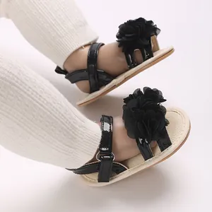 Primer plano de sandalias de verano para bebé niña con detalles de flores negras