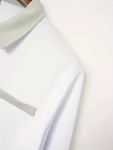 Detailopname van een wit getailleerd poloshirt met grijze kraag en nepzakontwerp