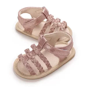 Gedetailleerde close-up van roze glitter gevlochten babysandalen met zachte rubberen zooltjes