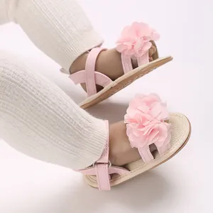 Detalle de sandalias rosas para bebé con aplique de flor de tela para niñas pequeñas.