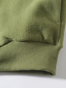 Detailaufnahme des grünen Fleece-Stoffs und des Rippbündchens an einem Herren-Sweatshirt