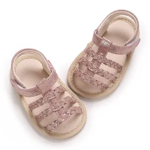 Detailweergave van roze glitter babysandalen met gevlochten bandjes en een rubberen zool
