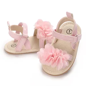 Primer plano de sandalias rosas para bebé con flores decorativas y cierres de velcro.