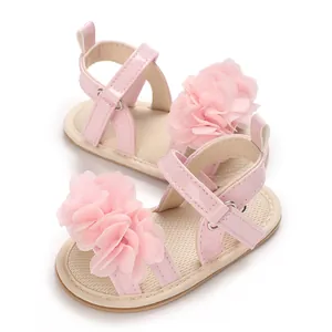 Vista detallada de sandalias rosas para bebé niña con una gran flor decorativa.