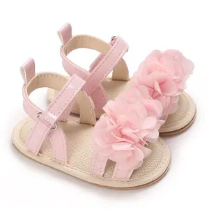 Primer plano de sandalias rosas de princesa para bebé con delicadas flores de tela en 3D