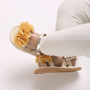 Primer plano de sandalias doradas para bebé con flor de tela amarilla y velcro