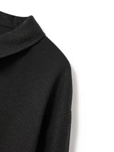 Dettaglio ravvicinato della trama del tessuto a nido d'ape nero sul colletto da uomo
