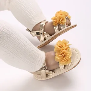 Detalle de cerca de las sandalias doradas para bebés con flores grandes de color amarillo.