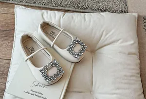 Gedetailleerde weergave van gebroken witte ballerina's met elegante strass gesp