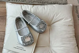 Detailopname van zilveren ballerina's met fonkelende strass-gesp op een kussen.