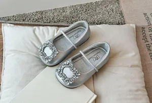 Detail van zilveren ballerina's voor meisjes met vierkante strass gesp en zachte zool.