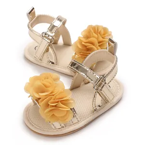 Detalle de sandalias doradas para bebé con hermosos adornos de flores de tela amarilla.