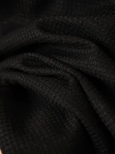 Primo piano della texture del tessuto a maglia waffle nero di una giacca da uomo