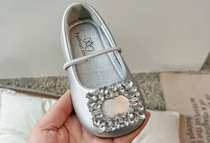 Detailopname van zilveren ballerina's met vierkante neus en strassteentjes