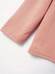 Macro detail van roze herenpolo met lange mouwen die de textuur van de piqué stof laat zien.