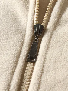 Nahaufnahme des hochwertigen Reißverschlusses an einem cremefarbenen Fleece-Sweatshirt