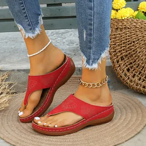 Vista detallada de sandalias de cuña rojas con diseño de mariposa en relieve para mujer.