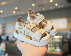 Vista dettagliata di sandali crema per bambini con suole morbide e design con orecchie di orso