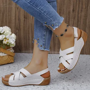 Detail view of white wedge sandals with crisscross straps and thick wood-grain sole.