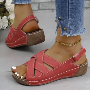 Detail view of stylish red wedge sandals with cross-strap design and white stitching.