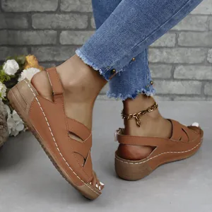 Detailed side view of brown platform wedge sandals with white stitching and buckle strap