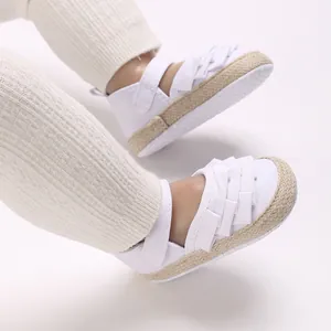 Primo piano di scarpe bianche da bambina primi passi con suola morbida e fiocco