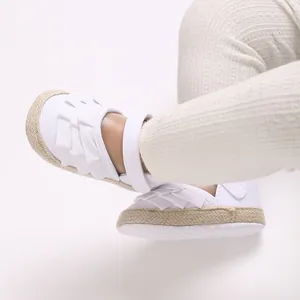 Dettaglio di scarpe primi passi bianche per neonata con volant e suola morbida.