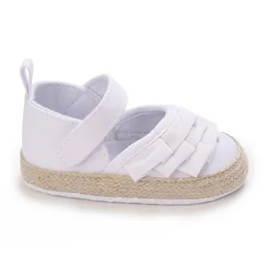 Vista dettagliata di scarpe bianche per bambina con volant e suola morbida intrecciata