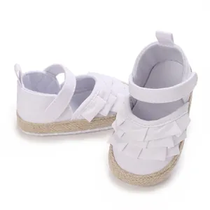 Dettaglio scarpe neonata bianche con volant eleganti e suola in stile espadrillas morbida