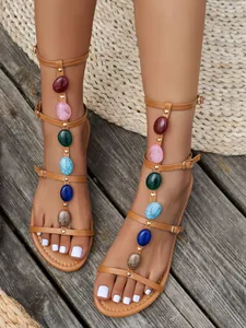 Close-up of bohemian gladiator flat sandals with colorful stones and adjustable straps.