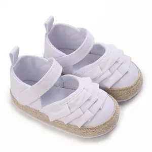 Dettaglio scarpe primi passi bianche per neonata con decorazione a volant e suola morbida