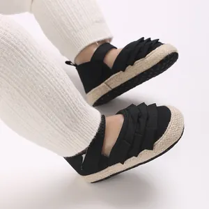 Primo piano di scarpine nere per neonati con volant e suole in espadrillas intrecciate