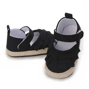 Primo piano di scarpe primi passi nere con volant per neonata e suola morbida intrecciata