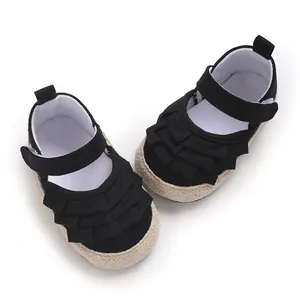 Dettaglio scarpe primi passi per neonata in tela nera con volant e suola in iuta morbida