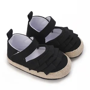 Dettaglio di scarpe da camminata nere per neonata con volant e suola in stile espadrillas